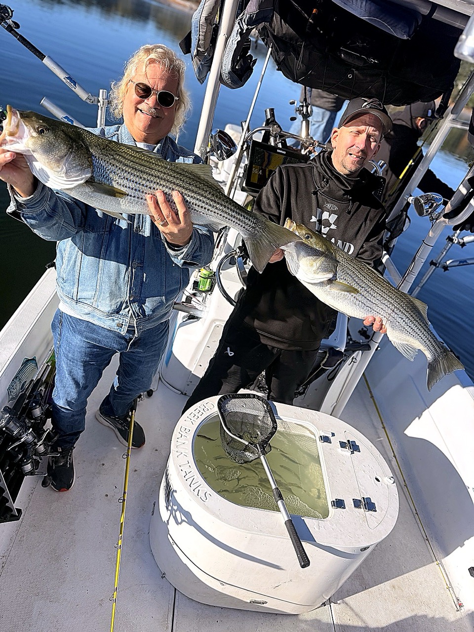 Lake Lanier Striper Fishing Report – October 20, 2026 Two Lake Lanier Striper Snipers clients holding striped bass beside the bait tank