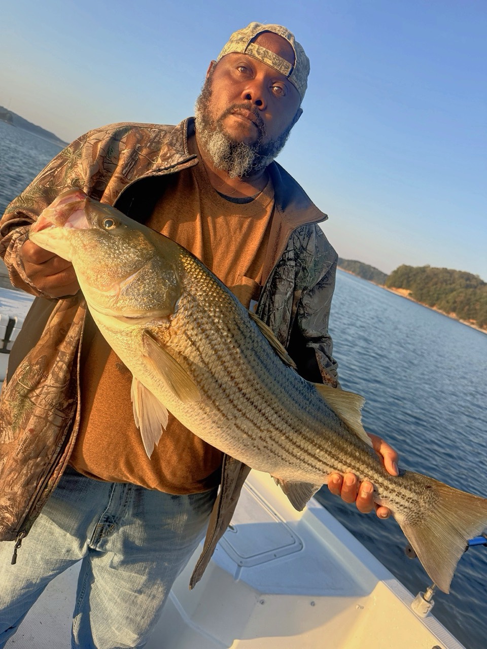 Lake Lanier Striper Fishing Report – October 19, 2026 Lake Lanier charter guest holding a striped bass at sunrise