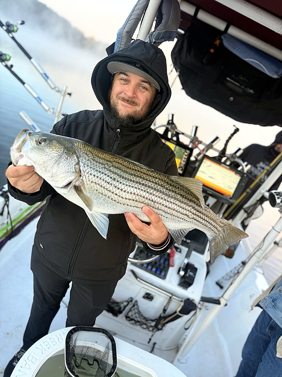Lake Lanier Striper Fishing Report – October 20, 2026 Lake Lanier charter guest holding a fall striped bass near the boat console