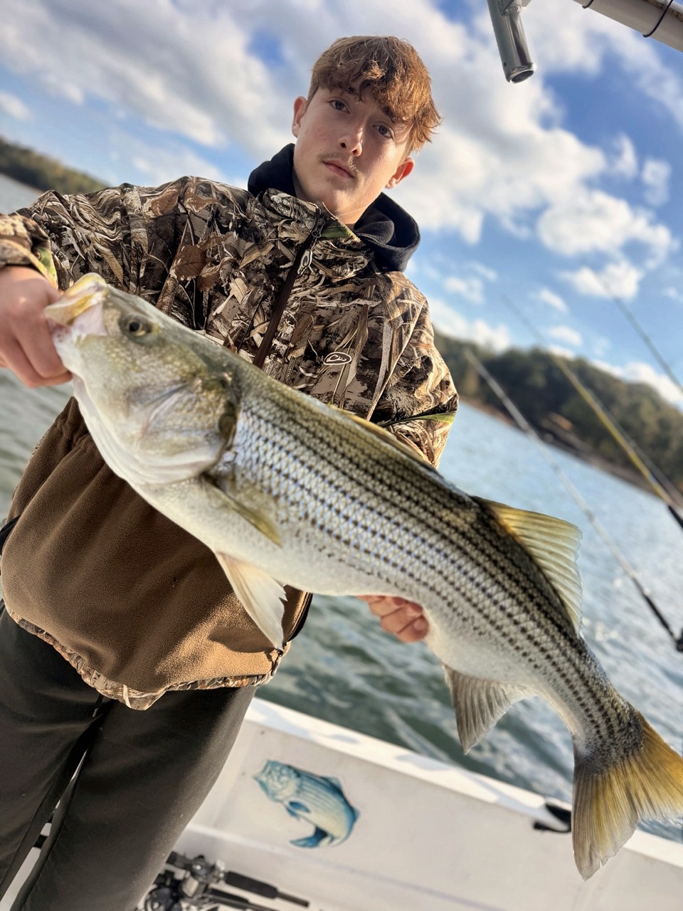 Lake Lanier Striper Fishing Report – October 24, 2026 | Tough Conditions, Quality Fish & Fall Migration Teen angler holding a large striped bass during a family trip on Lake Lanier
